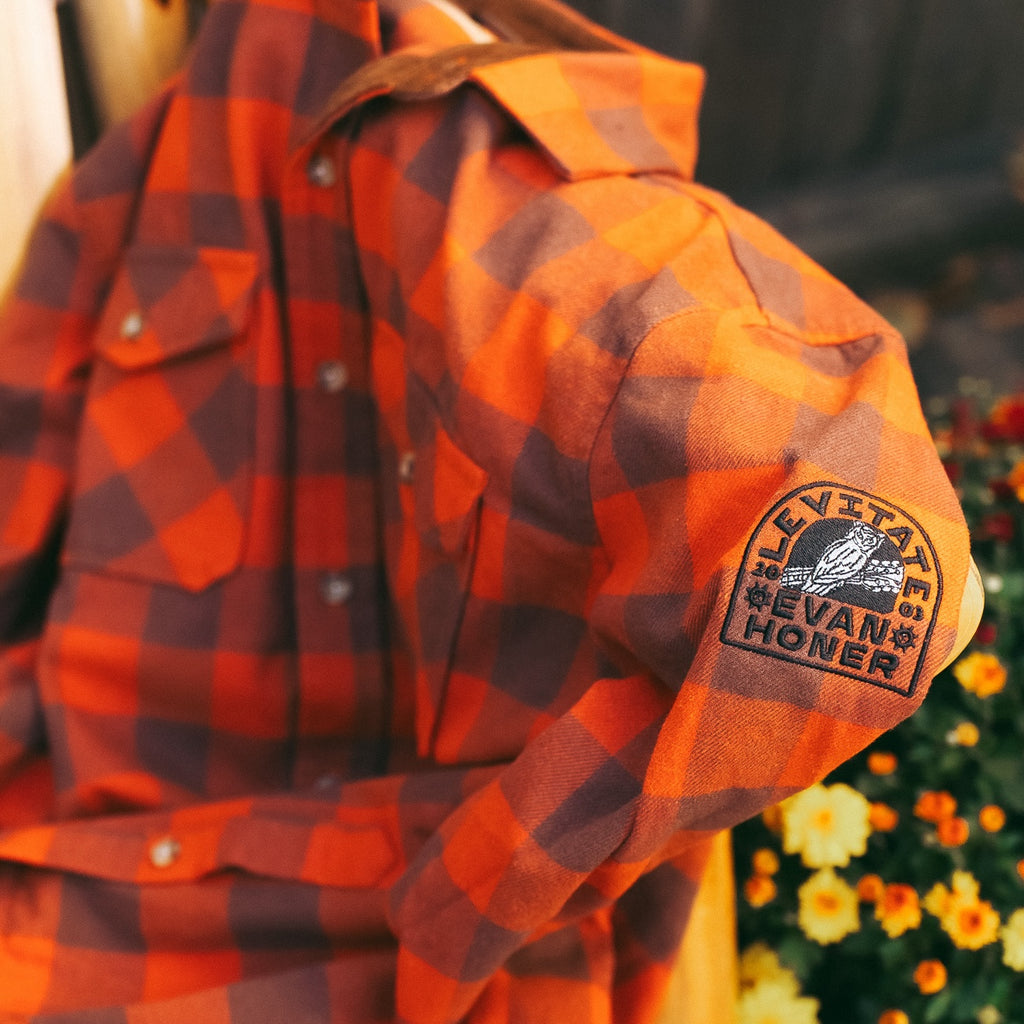 Levitate x Evan Honer Original Flannel, sleeve: close-up of the black Evan Honer owl patch on the left sleeve, with Fall mums behind