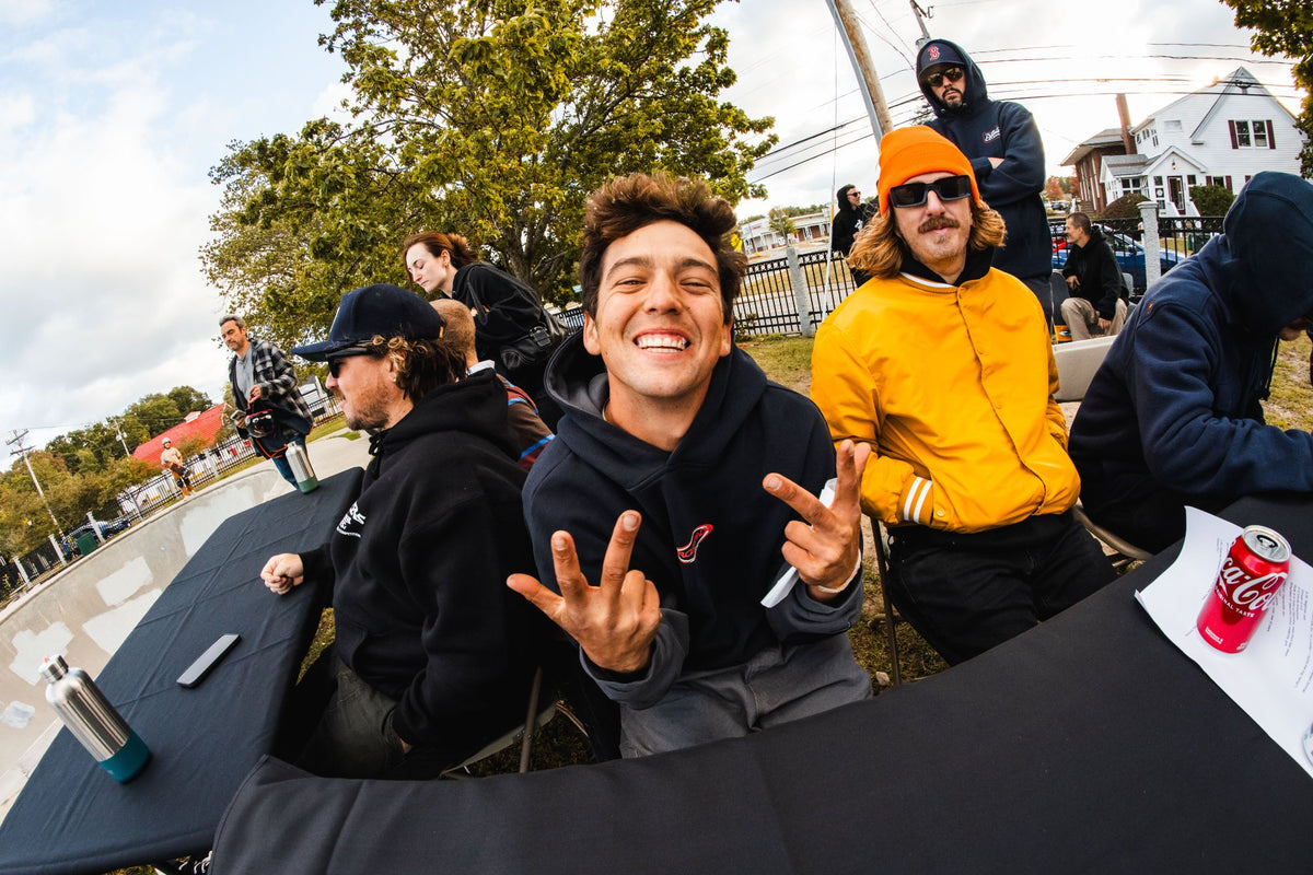 Grinning spectator in a navy hoodie throwing up hand signs trackside at the Shark Belly Classic