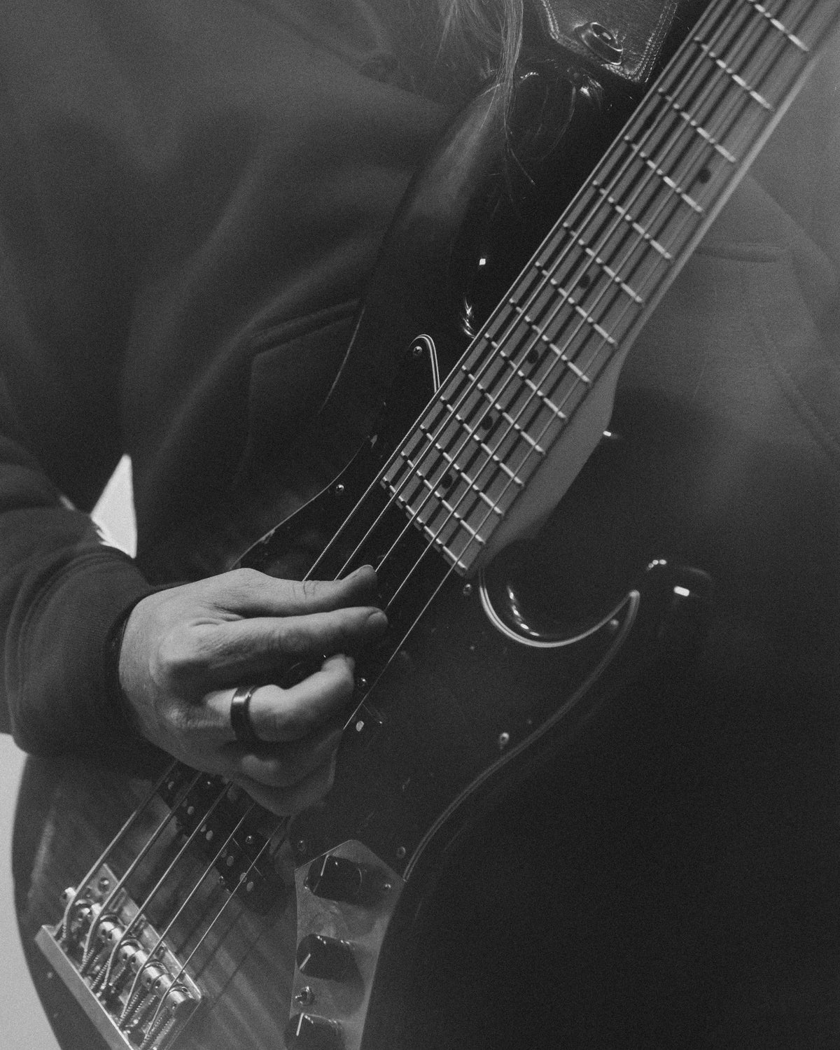 Black-and-white close-up of a bass guitar neck mid-song on night three
