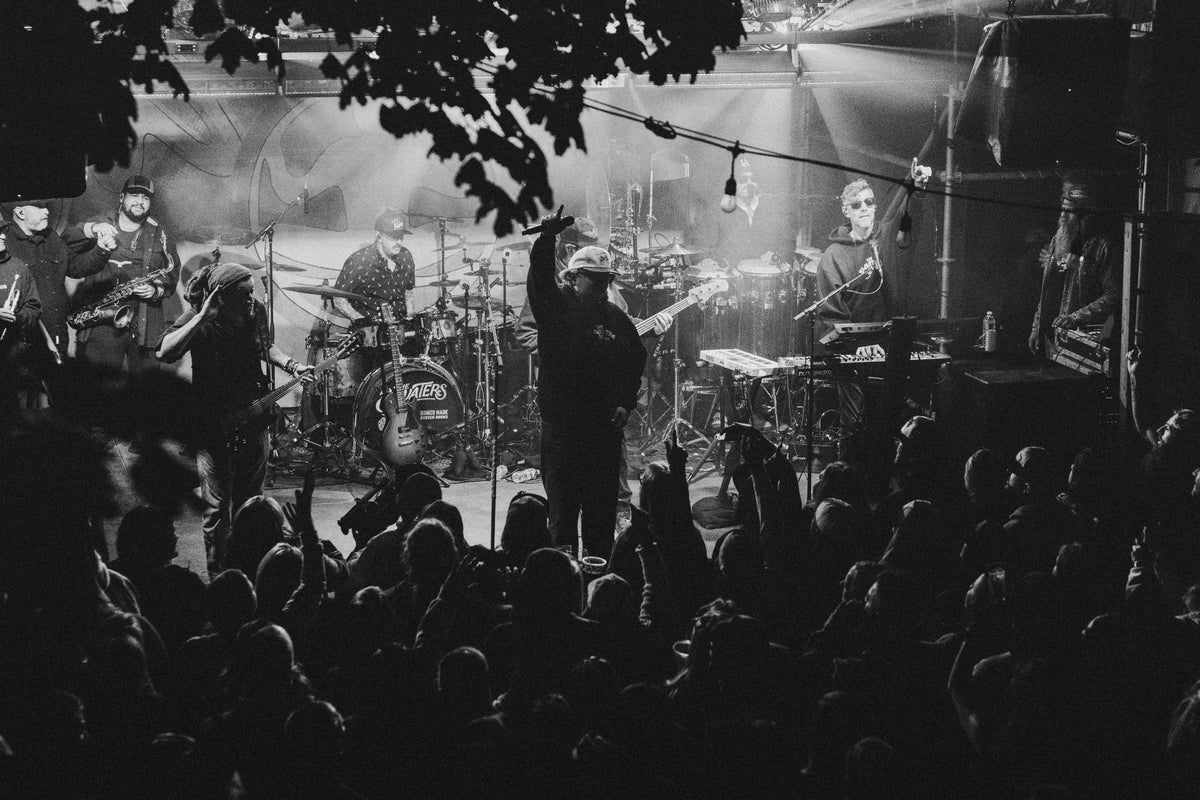 Black-and-white shot of a member of The Elovaters raising the mic to the crowd from the Backyard stage