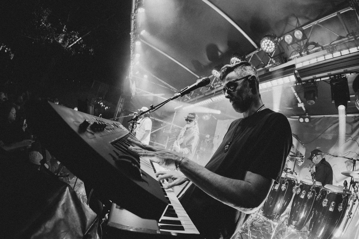 Black-and-white shot of hands on the keys with The Elovaters playing behind on night three