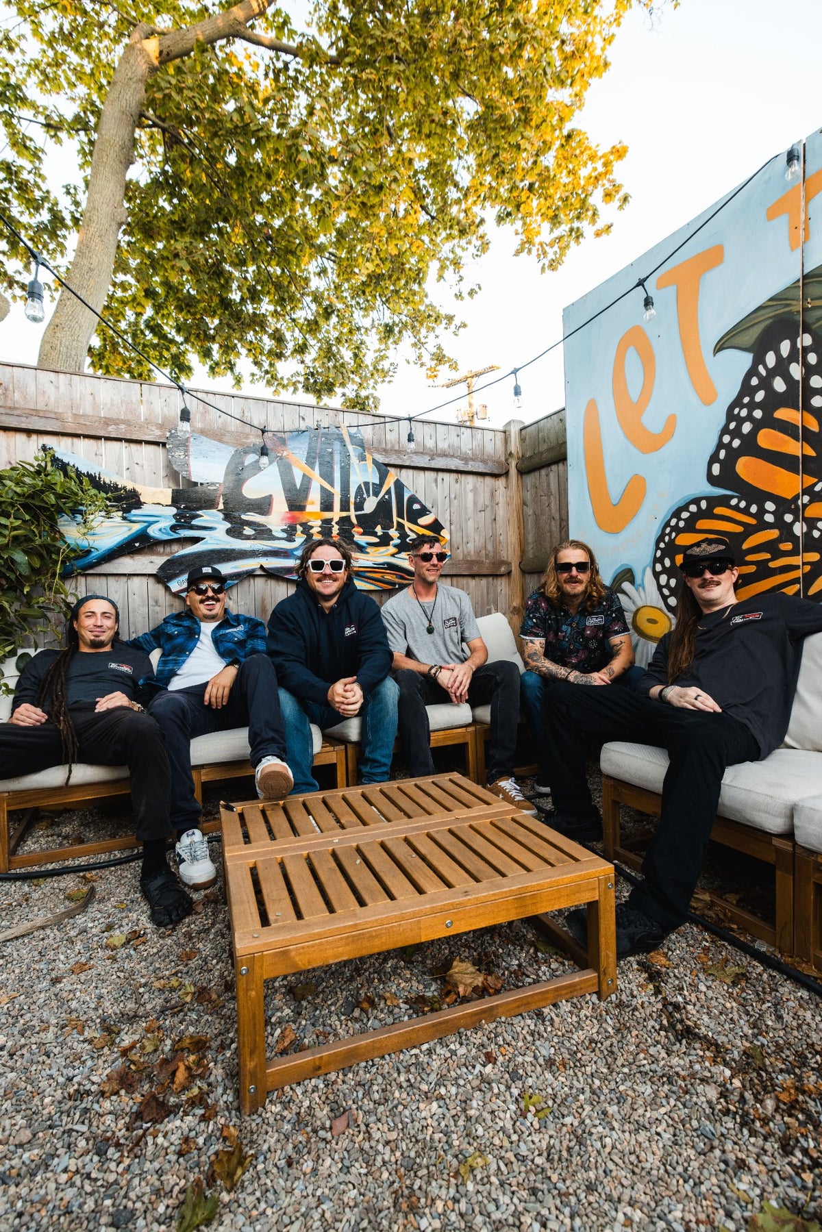 The Elovaters sitting together on the Backyard patio couches in the new collab pieces