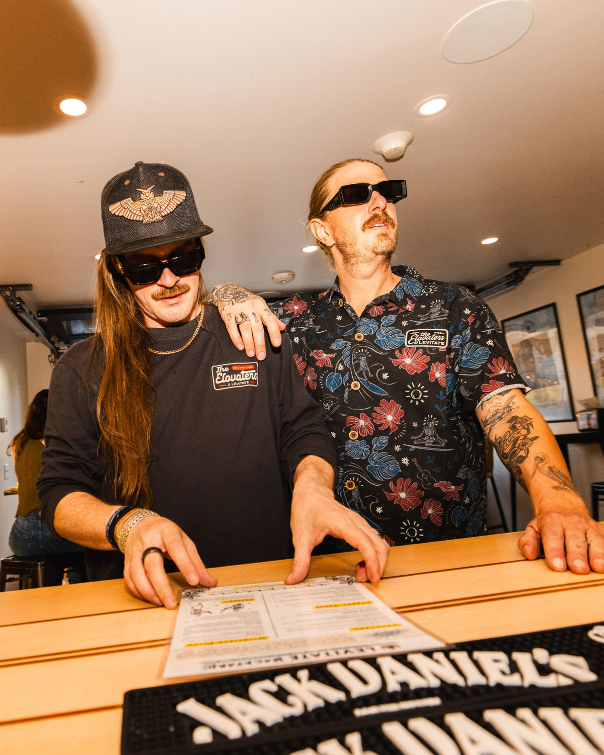 Two members of The Elovaters inside the Levitate Surf Shop, one wearing the Beach Cantina Shirt