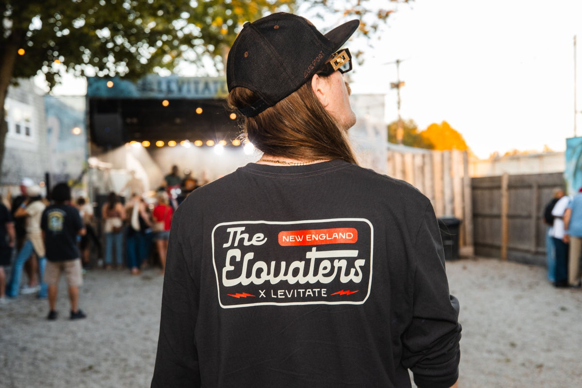 Back of the Levitate x Elovaters tee with The Elovaters script logo, worn in the Backyard