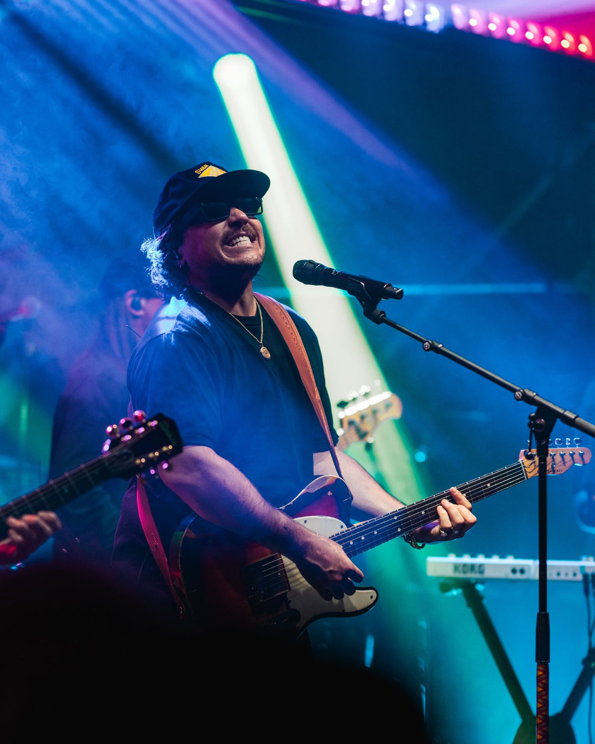The Elovaters' frontman singing and playing guitar under blue stage lights in the Backyard