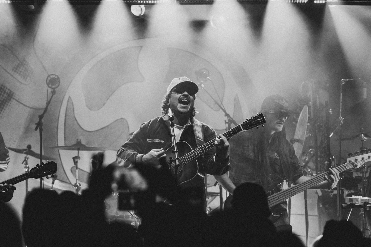 Black-and-white shot of The Elovaters' frontman singing with an acoustic guitar