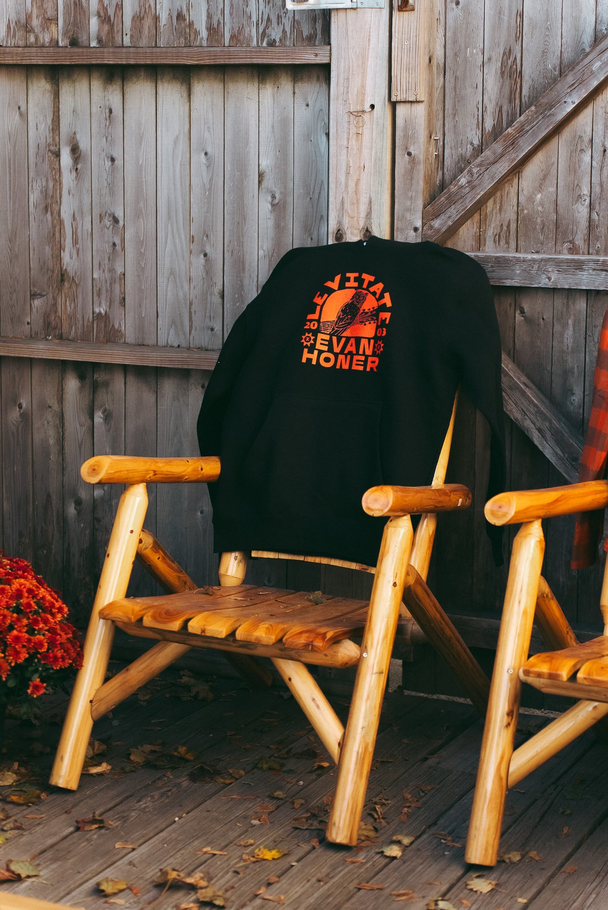 Levitate x Evan Honer hoodie and Original Flannel hung on wooden chairs against a shingled wall