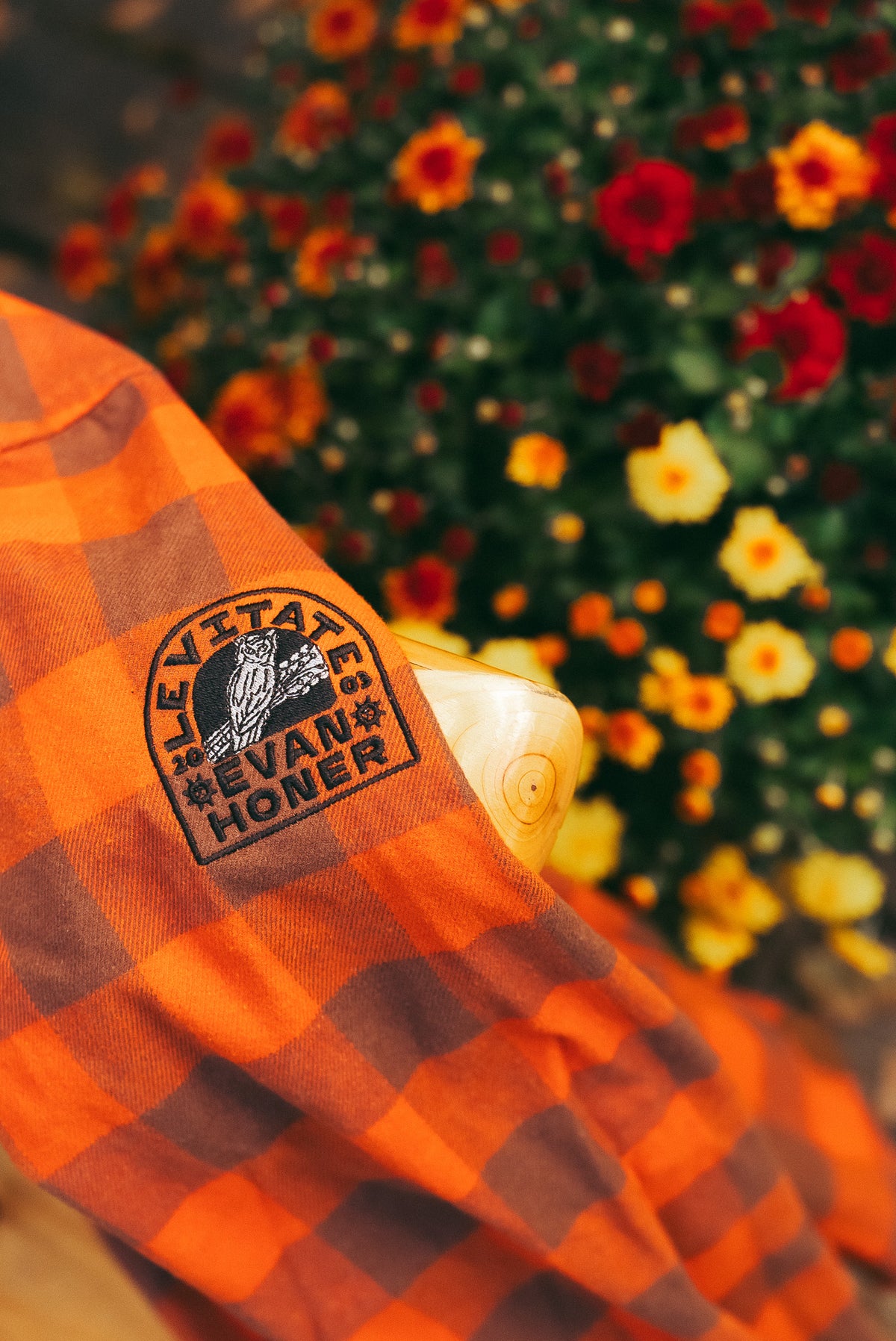 Close up of the sleeve patch on the Levitate x Evan Honer Original Flannel beside fall mums
