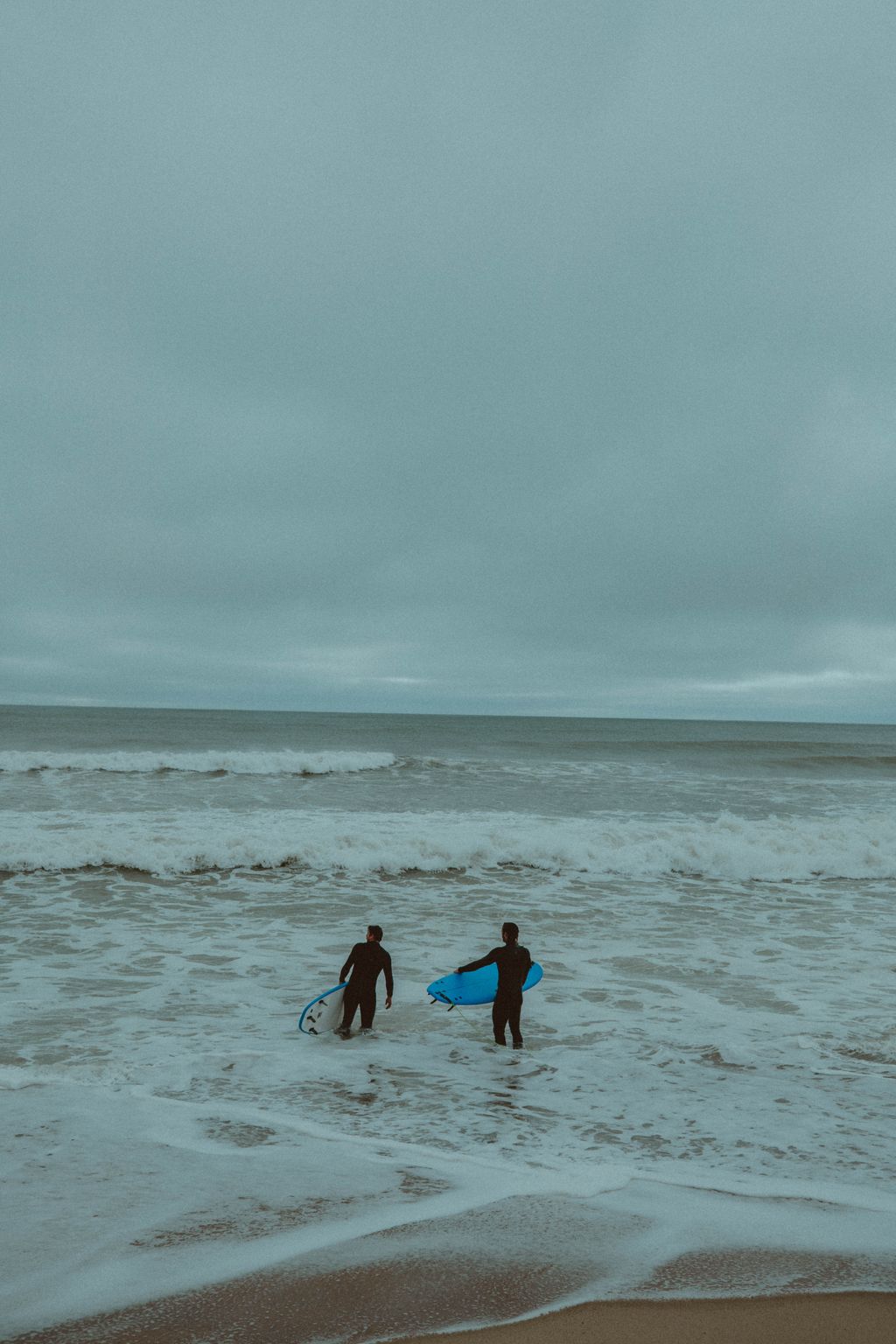 Evan Honer and a friend wading into the whitewater with surfboards behind Cisco on Nantucket