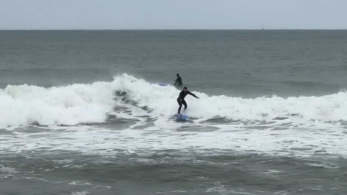 Surfer riding whitewater on a blue softtop behind Cisco on Nantucket