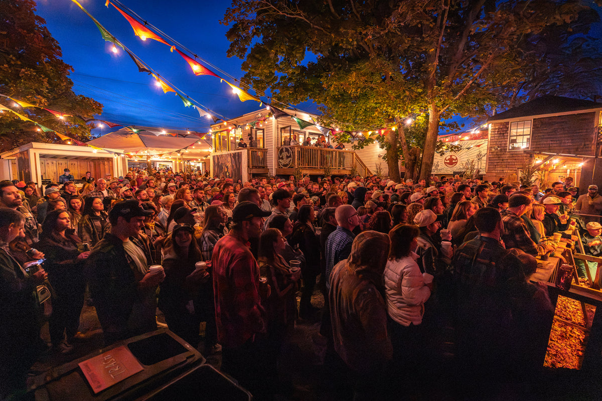 Flannel Jam crowd under string lights at dusk in the Levitate Backyard in Marshfield
