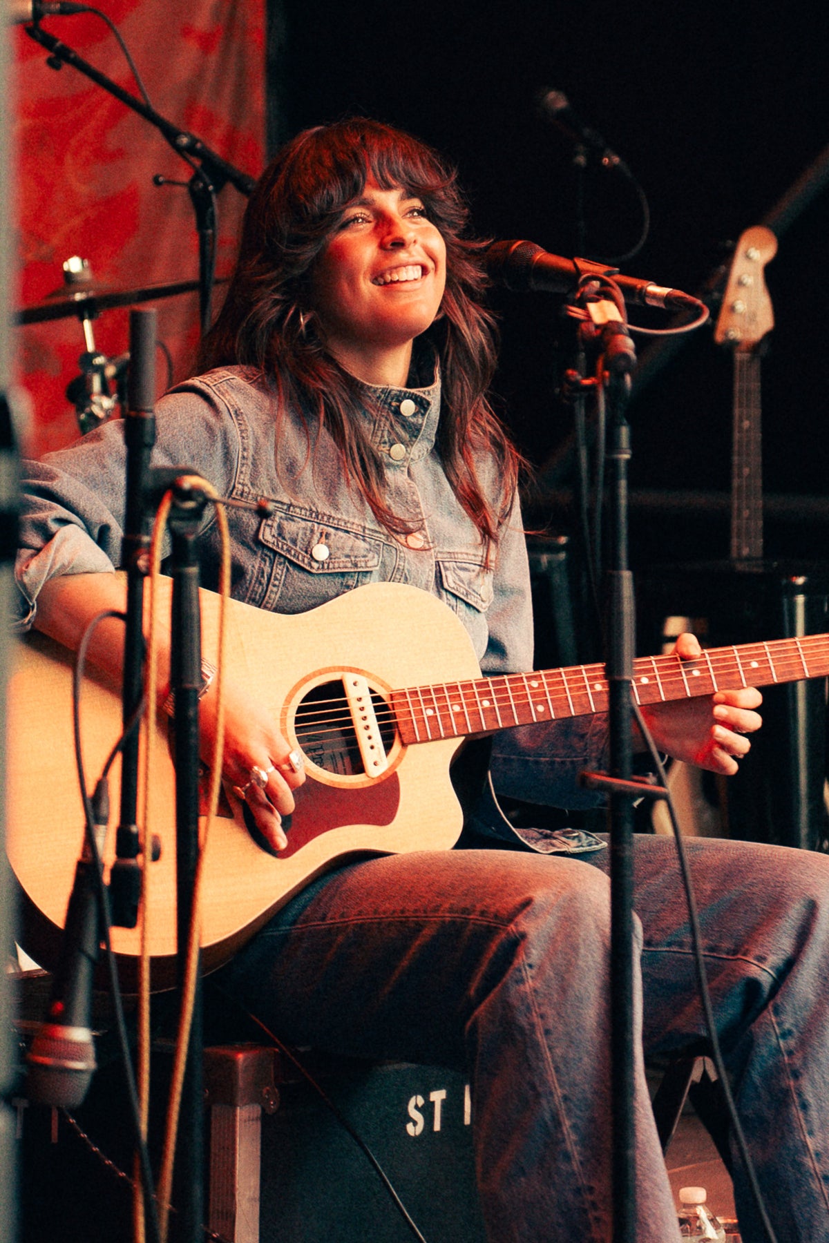 Steph Strings singing with an acoustic guitar on the Flannel Jam stage in Marshfield