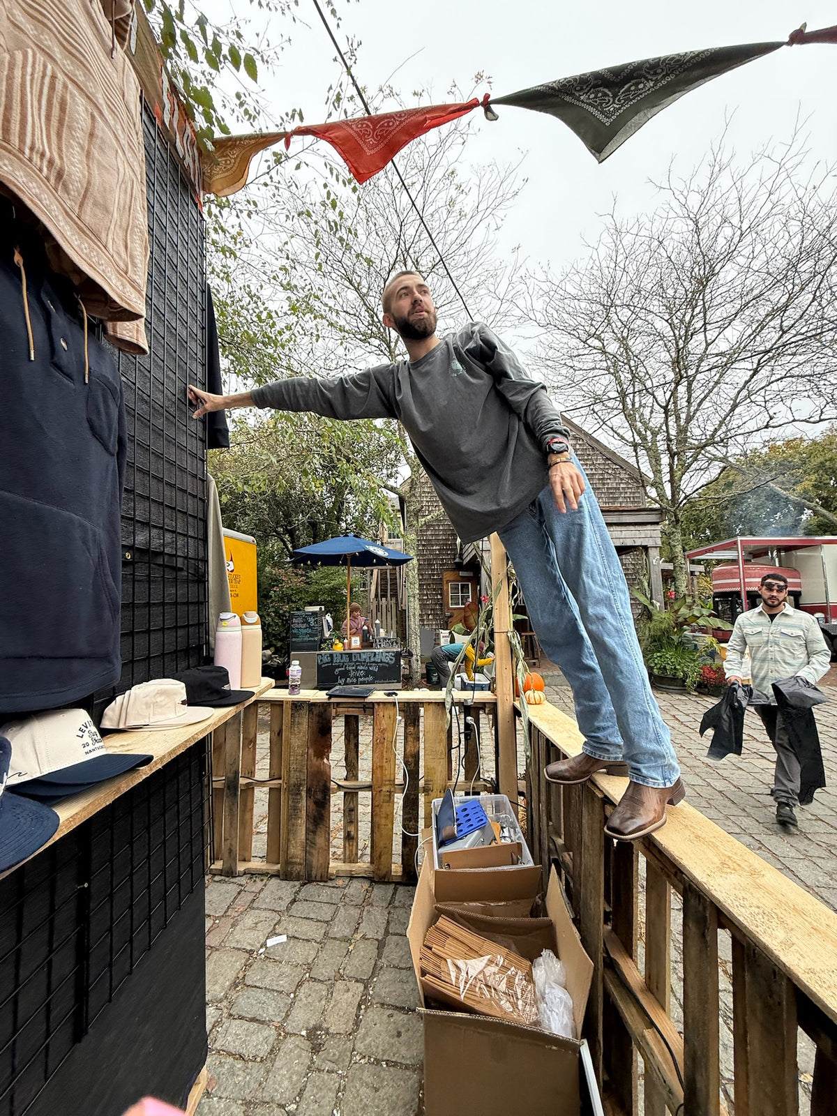Crew member stretching to hang pennant flags over the merch shop at Cisco Brewers