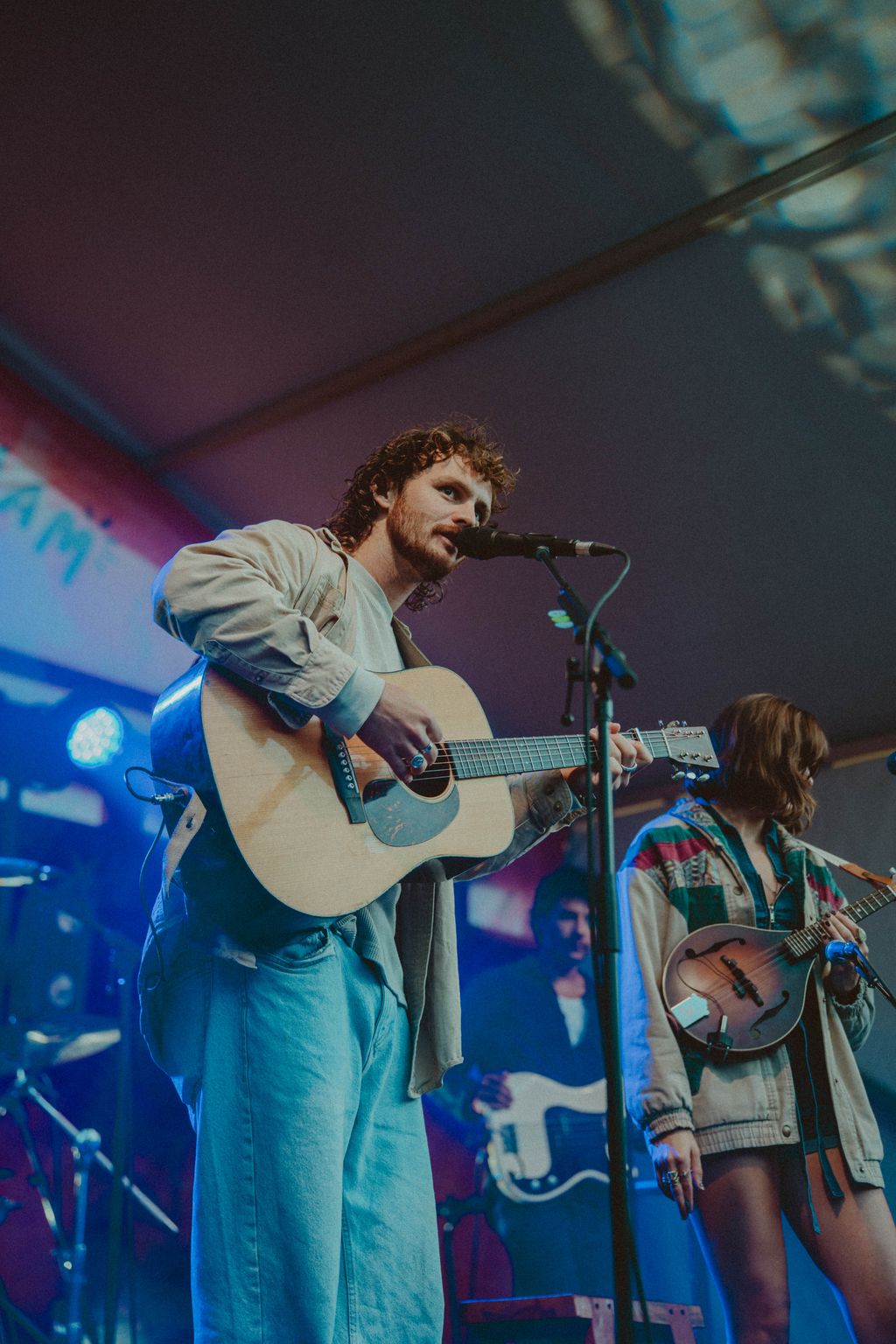 Evan Honer singing with an acoustic guitar beside a bandmate on the Flannel Jam stage at Cisco Brewers